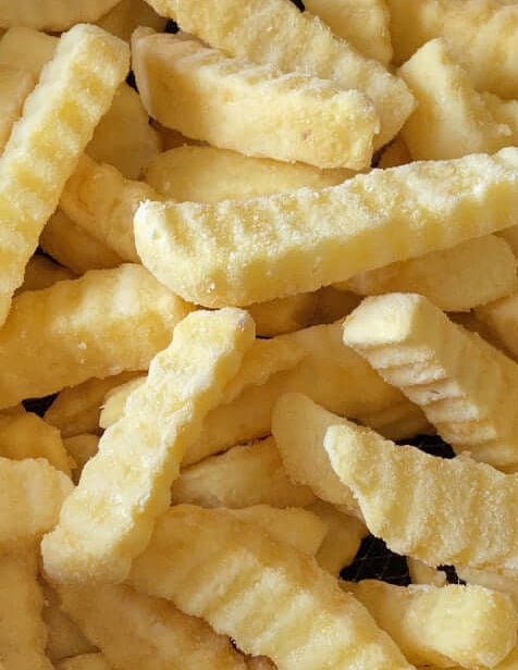 Close-up of crinkled potato fries frozen white background